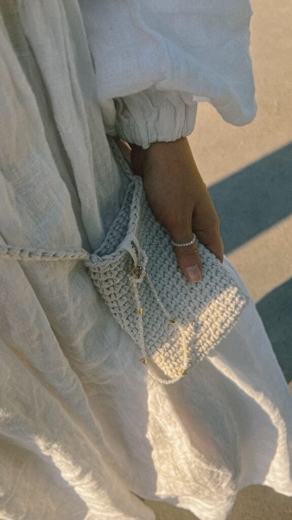 Bolso de crochet terminado, sostenido en la mano al sol